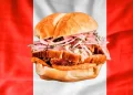 se muestra el pan con chicharron, de fondo la bandera peruana