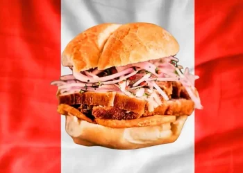 se muestra el pan con chicharron, de fondo la bandera peruana