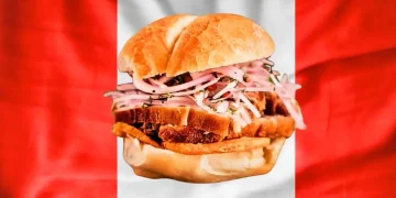 se muestra el pan con chicharron, de fondo la bandera peruana